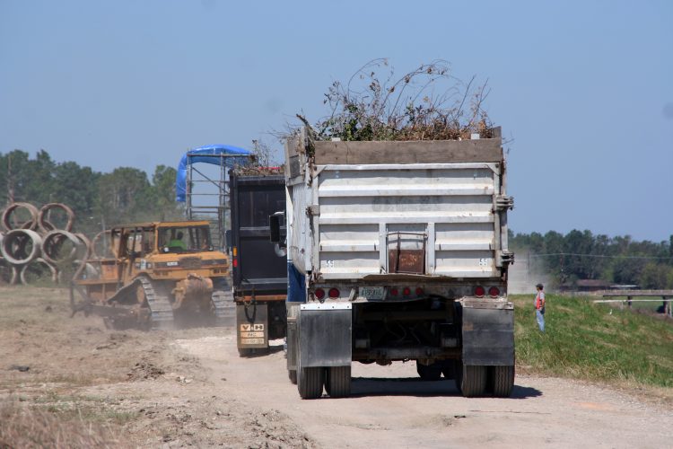 Truck hauling away brush on a job site.