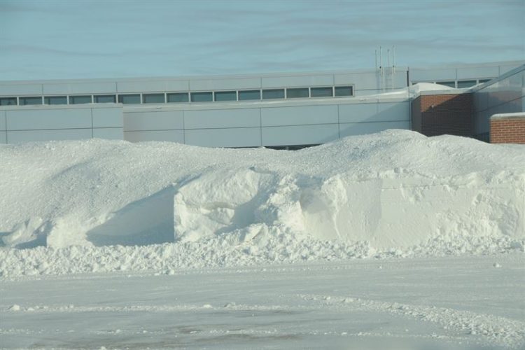 Large parking lot snow pile in front of an industrial building